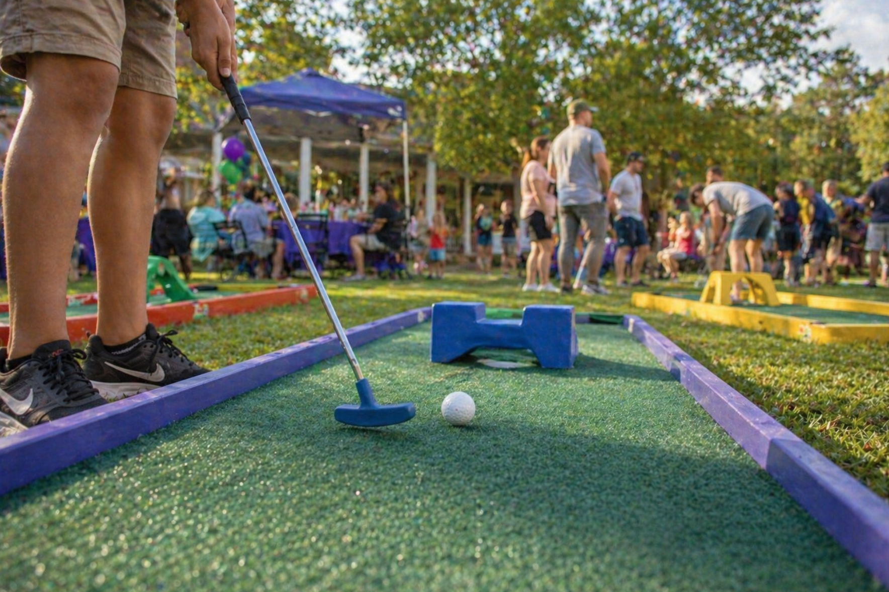 Guests playing portable mini golf rentals in Mauldin, SC with a close-up action shot showing realistic turf lanes and fun putting obstacles. Mini golf rentals in Mauldin, South Carolina are perfect for birthday parties, graduation parties, and family events. This clean portable setup creates entertainment for both children and adults.
