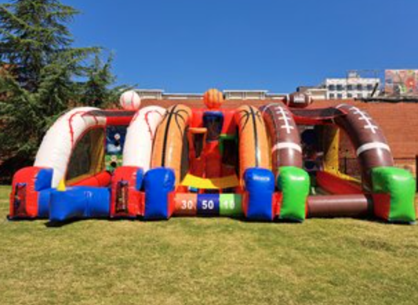 Sports challenge inflatable game with baseball, basketball, football, and soccer-themed play stations in one large interactive setup.