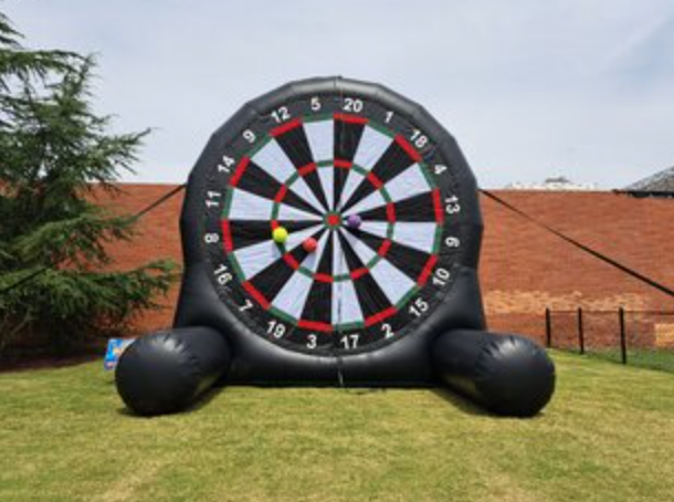 Giant inflatable soccer dartboard game with oversized dart target, black frame, and soccer balls attached to the board.