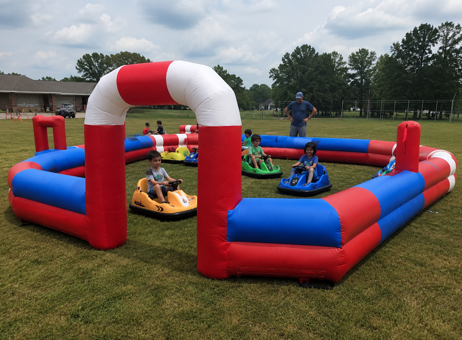 Children in yellow, blue, green, and red bumper cars driving inside an inflatable arena.