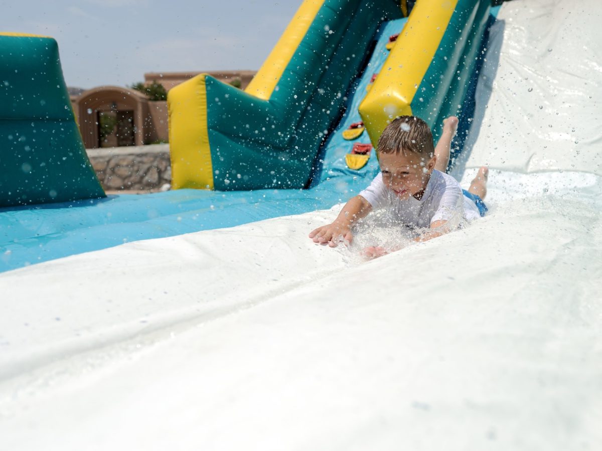 Young child splashes down a colorful inflatable slide during water slide rentals in Mauldin, SC. Young child splashes down a colorful inflatable slide during water slide rentals in Mauldin, SC.