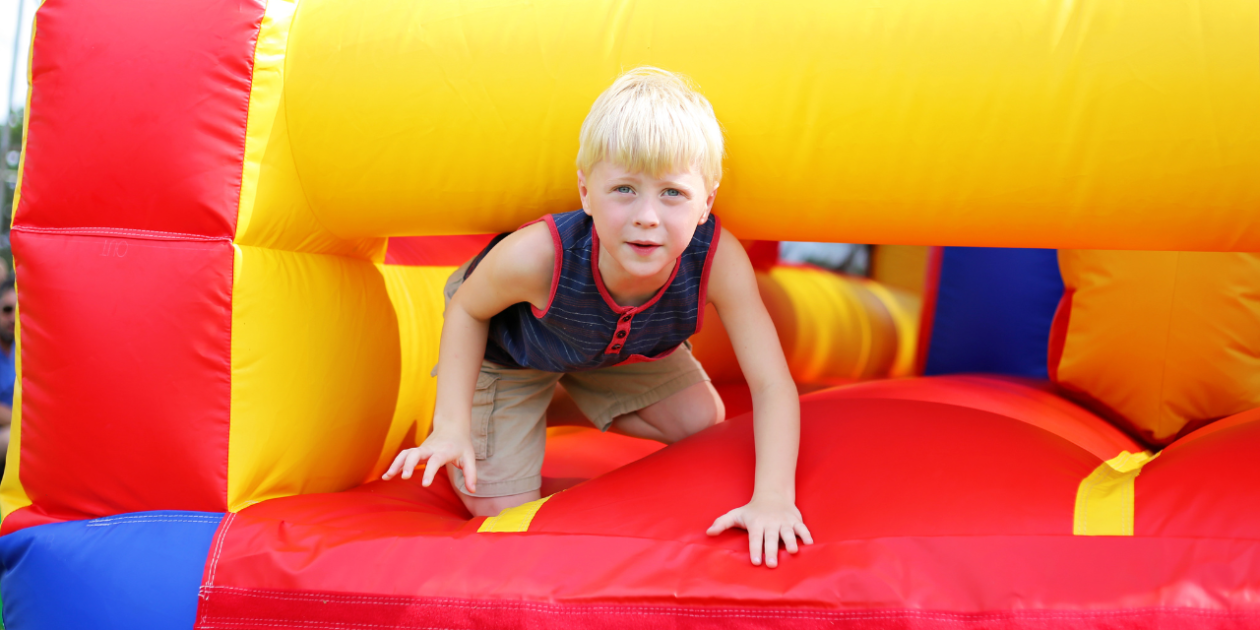 Child playing on a colorful inflatable obstacle course during autumn adventures in Greenville SC with Party To Go outdoor rentals.