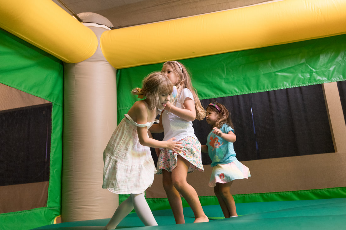 Kids jumping inside a green and yellow bounce house at a fall event with outdoor rentals in Greenville SC provided by Party To Go.