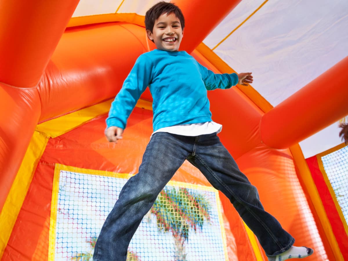 Kid enjoying a bounce house rental at a backyard graduation party, showcasing popular 2026 event entertainment options
