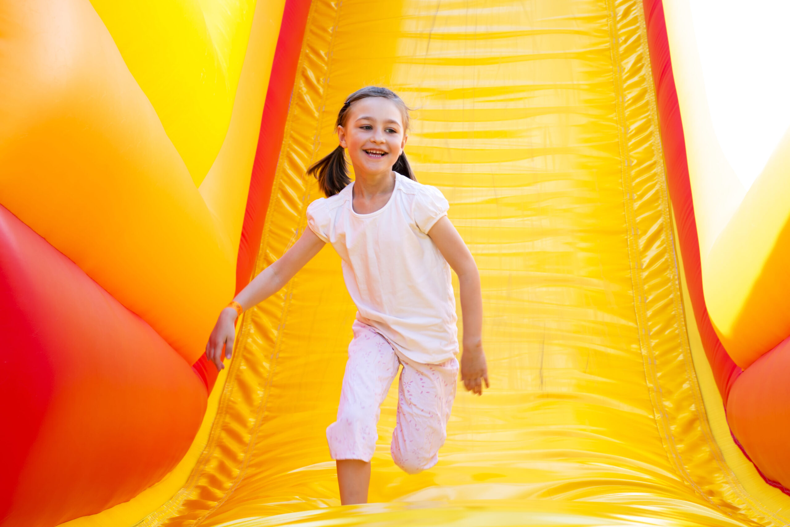 Child enjoying a bright yellow inflatable slide at a fall event in Greenville, SC
