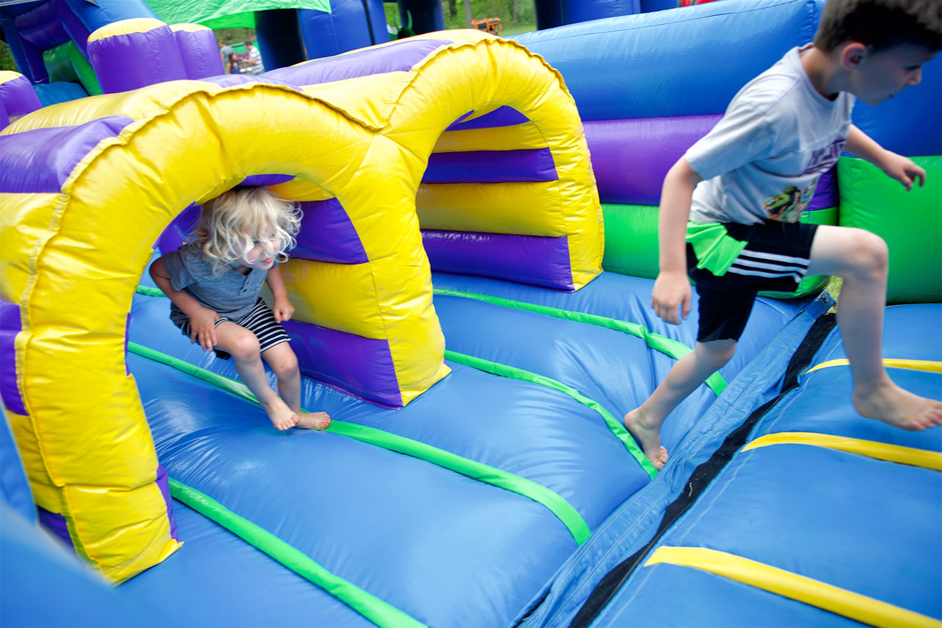 Kids racing through a colorful inflatable obstacle course at a party in Easley, SC, featuring tunnels, climbing sections, and soft landing zones.