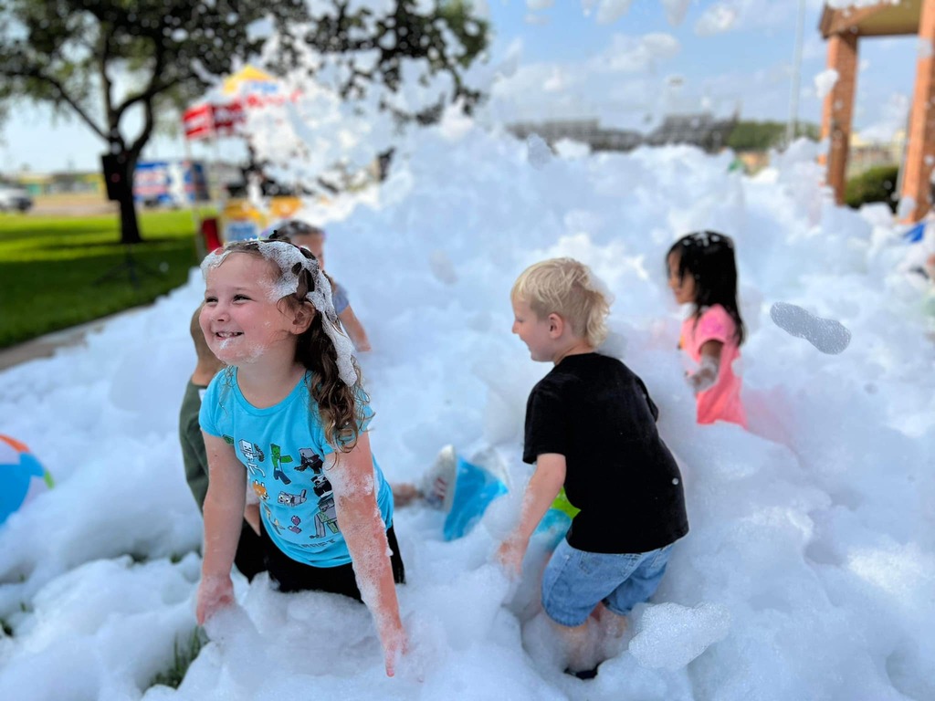 Young children laughing and playing in piles of foam during a sunny outdoor foam party in Greer, SC. Young children laughing and playing in piles of foam during a sunny outdoor foam party in Greer, SC.