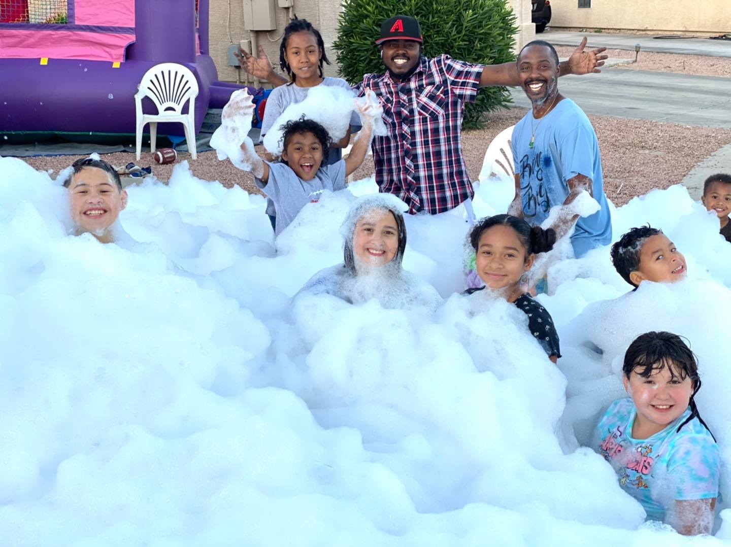 A group of kids and adults smiling and covered in foam at a lively backyard foam party in Easley, SC. A group of kids and adults smiling and covered in foam at a lively backyard foam party in Easley, SC.