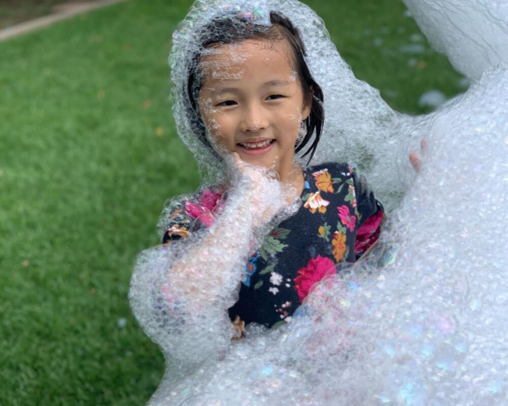 Child playing in soft, clean foam on green grass during a foam party in Parker, SC. Child playing in soft, clean foam on green grass during a foam party in Parker, SC.