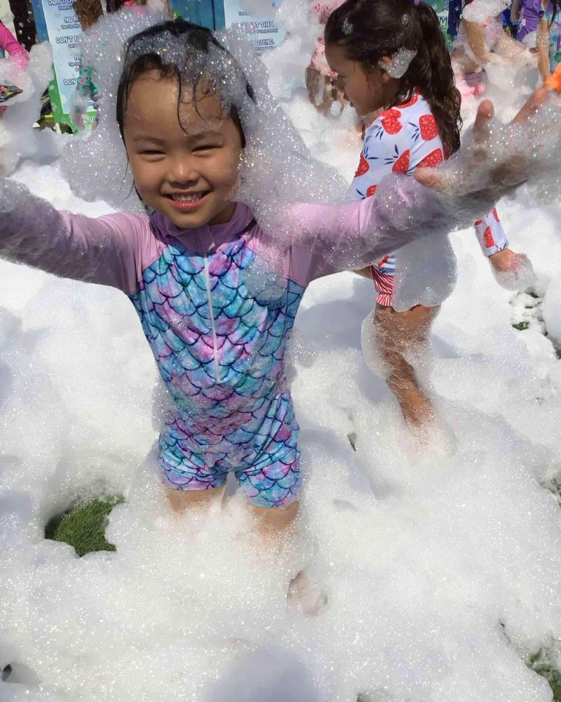 Young child playing joyfully in bubbles during a fun outdoor foam party in Berea, SC. Young child playing joyfully in bubbles during a fun outdoor foam party in Berea, SC.