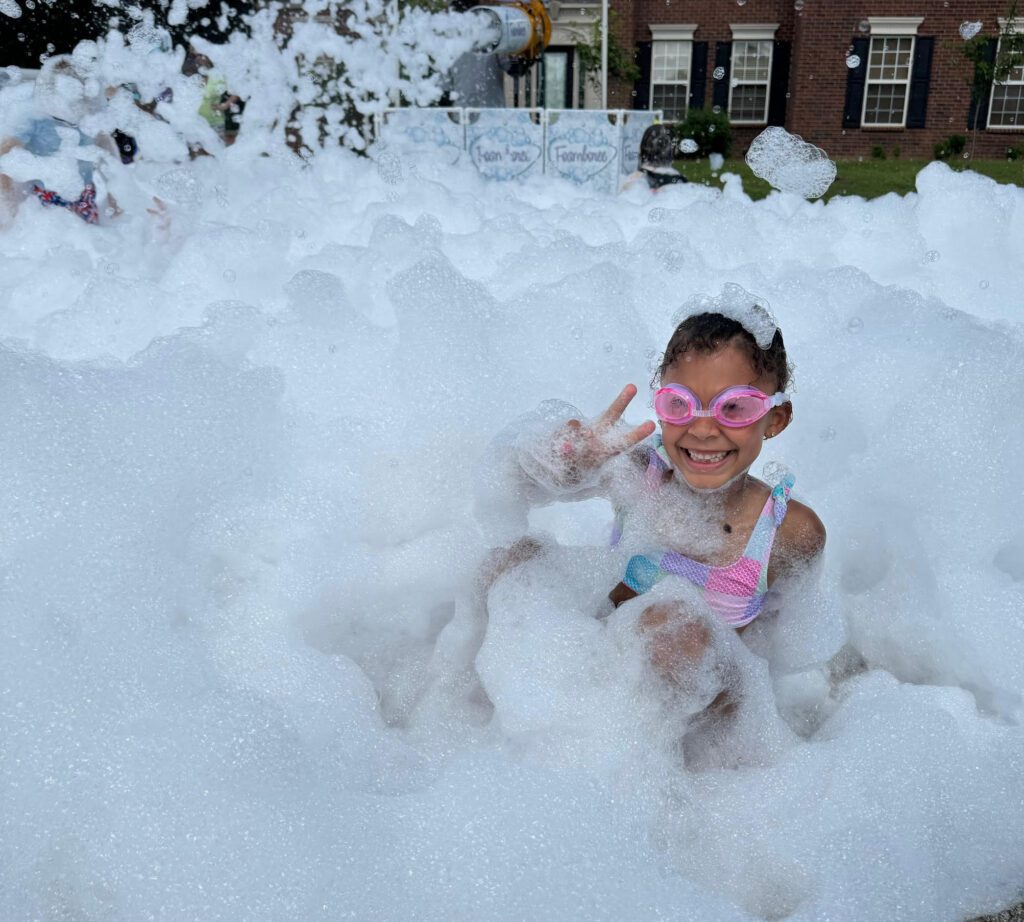 Smiling girl in goggles surrounded by foam from a professional foam machine at a Fountain Inn SC foam party.