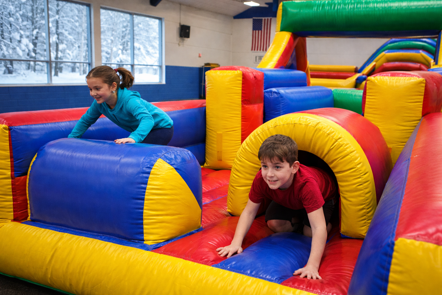 Two children safely using an enclosed indoor inflatable obstacle course inside a gymnasium during a winter event in Greenville, SC