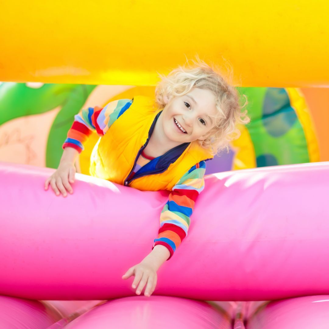 Smiling child playing on a colorful inflatable obstacle course at a party in Travelers Rest, SC, featuring soft padded barriers and bright, kid-friendly design.