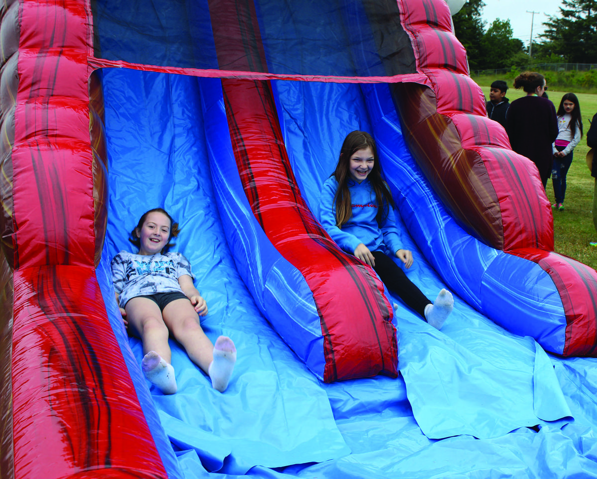 Two girls sliding down a double-lane inflatable at an outdoor event, showcasing Water Slide Rentals in Parker, SC for fun-filled community gatherings. Two girls sliding down a double-lane inflatable at an outdoor event, showcasing Water Slide Rentals in Parker, SC for fun-filled community gatherings.