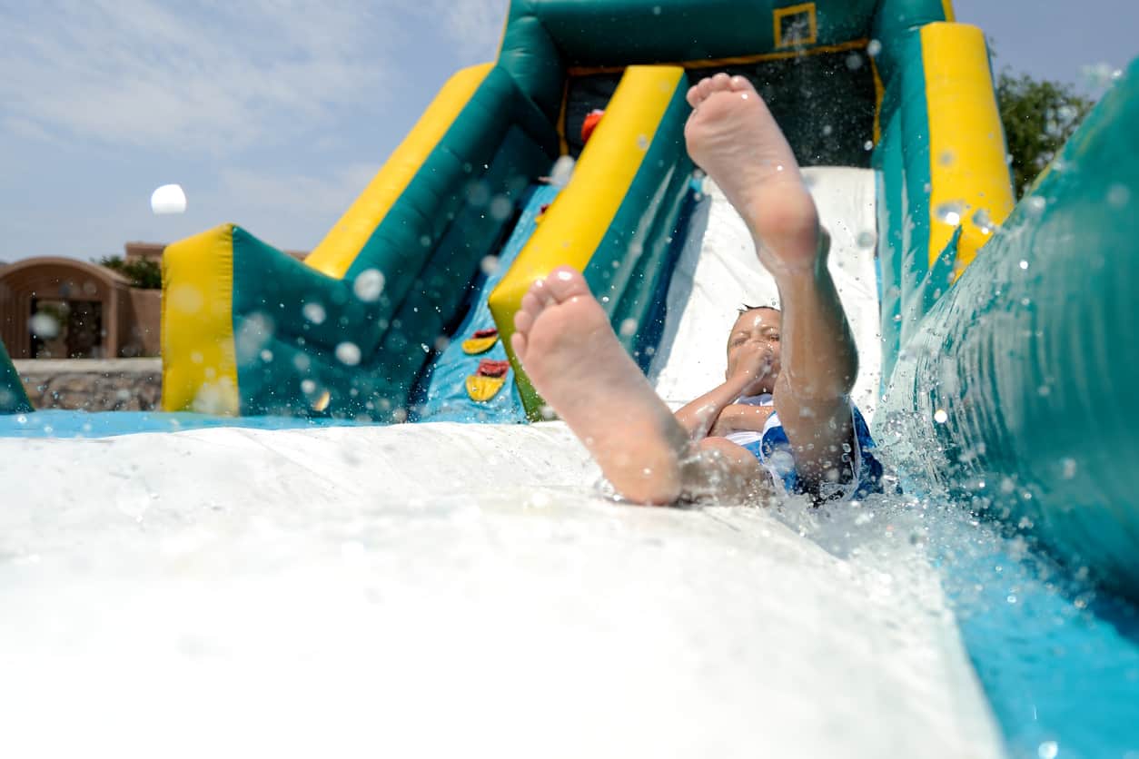 Child splashing at the bottom of a slide from our water slide rentals in Easley, SC.