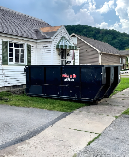 PHiLL It Up Disposal, LLC black dumpster placed beside a residential home with mountains in the background