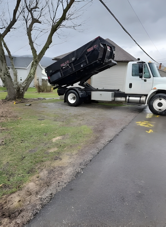 PHiLL It Up Disposal, LLC truck unloading a black roll-off dumpster in a residential driveway