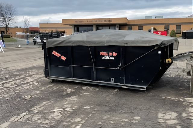 PHiLL It Up Disposal, LLC black dumpster in a commercial parking area