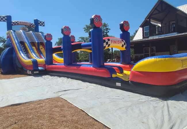 Big inflatable water slide rented at a house in Fort Worth with a long inflated landing and double lanes for racing