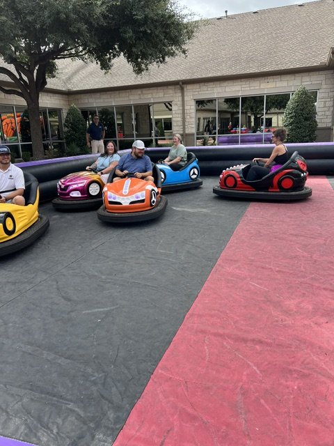 Adults riding inflatable bumper cars at a Cleburne, TX party rental event