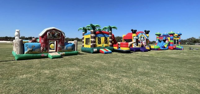 Lineup of combo bounce house rentals including toddler, tropical, and character bouncers set up in C…