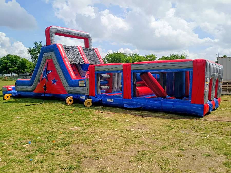 Giant red, white, and blue two piece inflatable obstacle course rental set up outdoors near Cleburne…