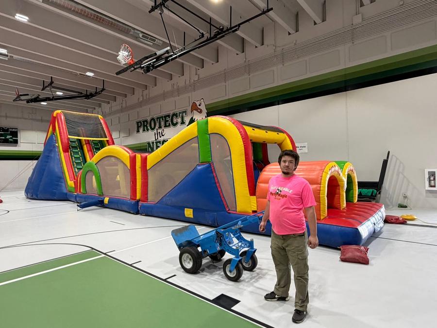 Inflatable Party Magic team member with a large indoor inflatable obstacle course set up in a Clebur…