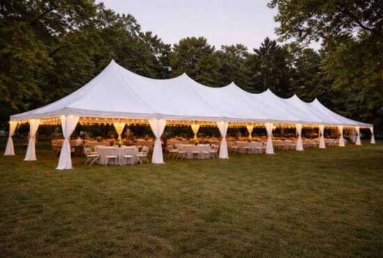 Premier Tents & Events large white frame tent with lighting and dining tables at an outdoor evening event