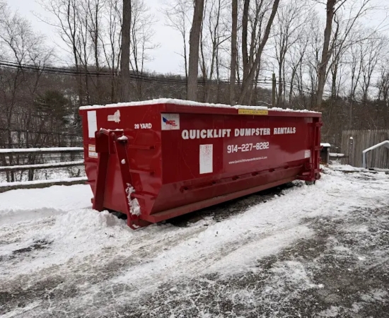 Red roll-off dumpster in a snowy lot from QuickLift Dumpster Rental