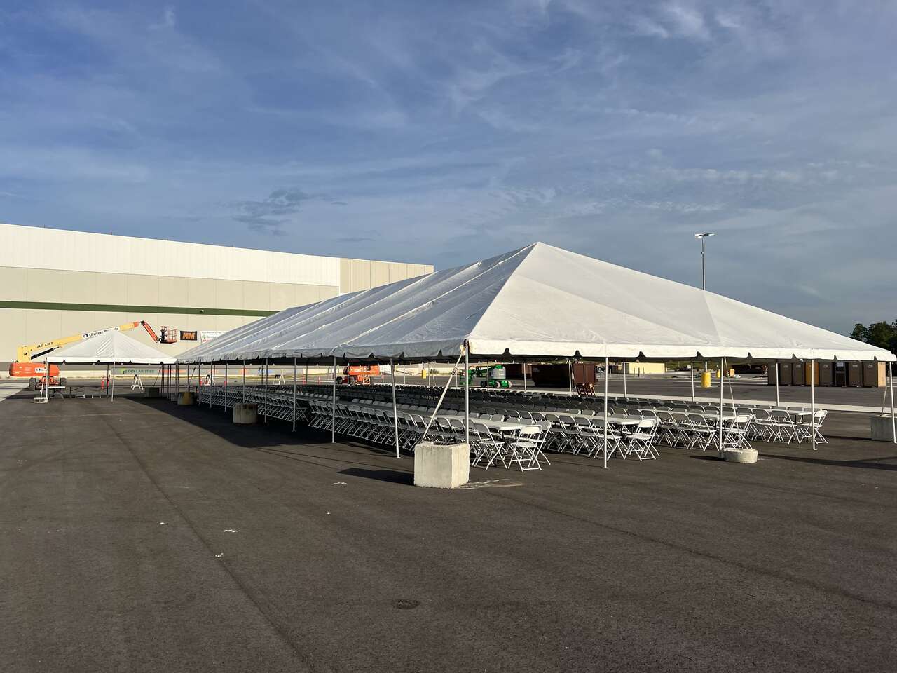 A large white event tent set up in a spacious outdoor area with rows of metal folding chairs neatly arranged underneath, ready for an event in Ocala, FL. The tent rental, provided by Rebound Party Rentals, showcases their capability to accommodate gatherings of significant size with professional setup.