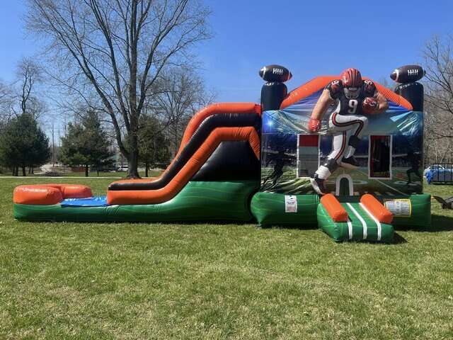Football-themed inflatable water slide rental in Maineville, OH, featuring a player tunnel entrance and football goalposts, perfect for sports-themed events and birthday parties, offered by Party Go Round.