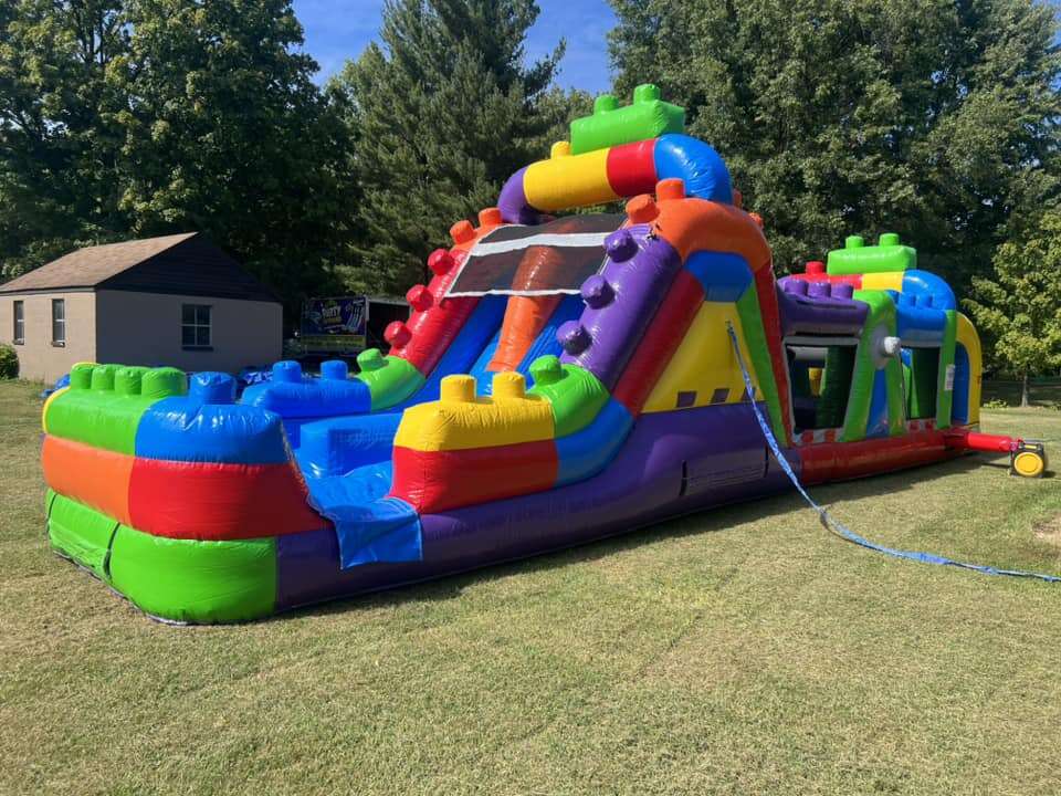 Massive multi-colored inflatable obstacle course from Party Go Round, featuring slides and tunnels, set up for active fun at a Maineville, OH outdoor event, ready to enhance any party with bounce house and water slide excitement.