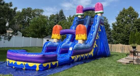 Large inflatable water slide rental set up in a backyard for a summer party by Roundhouse Inflatables