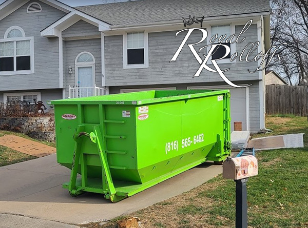 A green dumpster from Royal Rolloffs placed at an active construction site