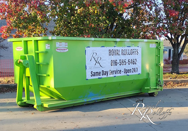 A green dumpster from Royal Rolloffs placed at an active construction site