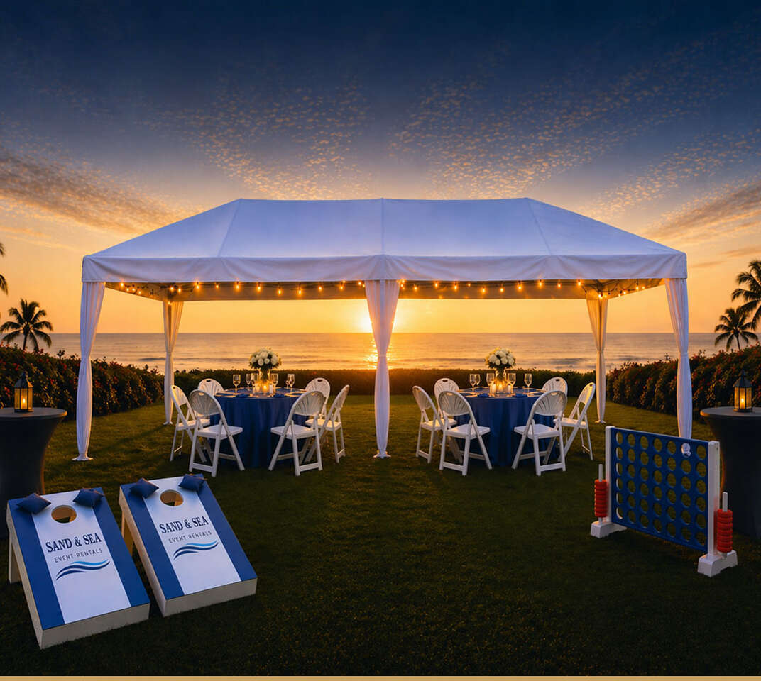 Beachside event rental setup with tent, seating, and lawn games at sunset