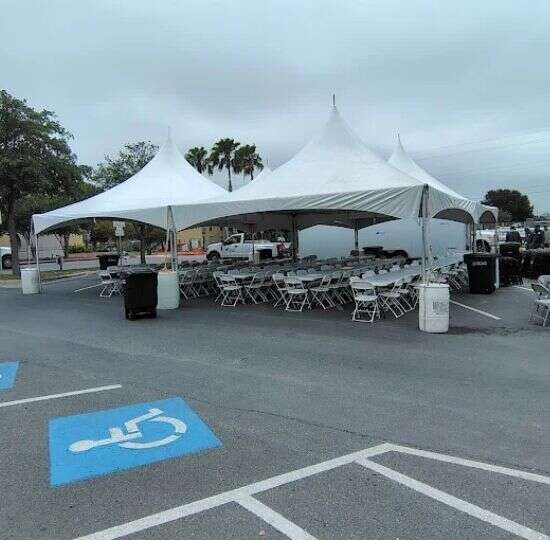 Outdoor white tent rental setup with tables and chairs by Sky High Rentals