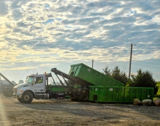 Truck unloading green roll-off dumpster at a site by Sparks Enterprises LLC Truck unloading green roll-off dumpster at a site by Sparks Enterprises LLC