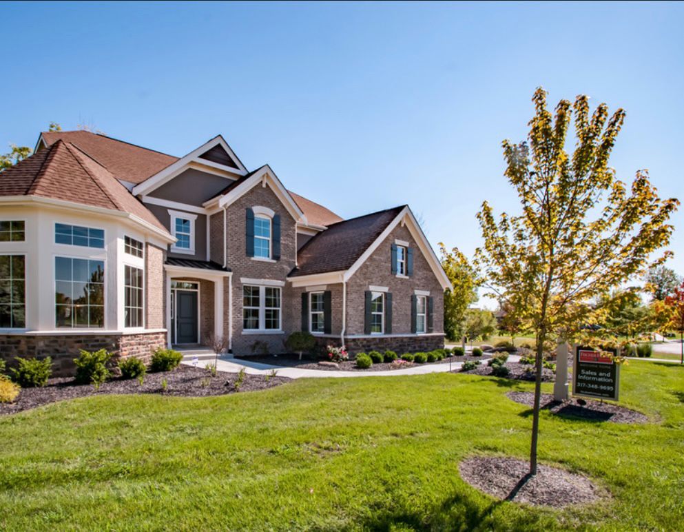 Two-story model home with landscaped yard and sales sign