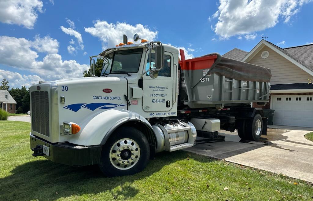 Transport Technologies dumpster truck parked in a residential neighborhood Transport Technologies dumpster truck parked in a residential neighborhood