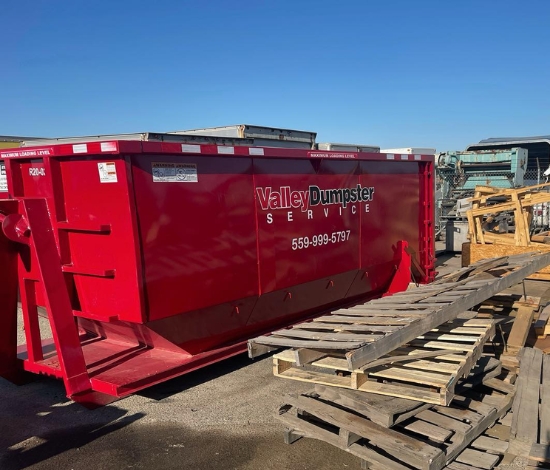 Red Valley Dumpster Service roll off container loaded on flatbed truck for delivery