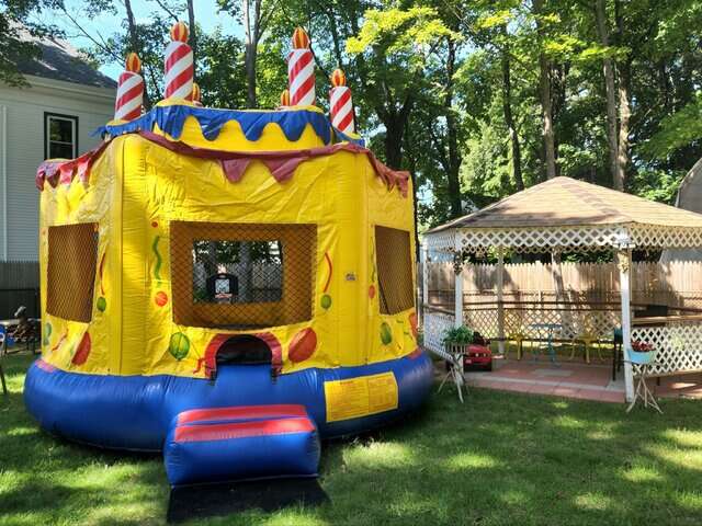 Vertical Entertainment inflatable birthday cake bounce house with candle decorations set up outdoors.