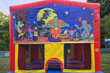 Halloween-themed inflatable bounce house by Vertical Entertainment featuring cartoon monsters and spooky decorations.