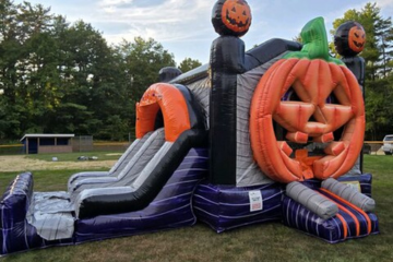Halloween-themed inflatable slide with a giant pumpkin entrance by Vertical Entertainment.