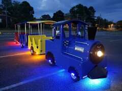 Colorful trackless train ride by We Bring the Party lit up at night for kids' entertainment. Colorful trackless train ride by We Bring the Party lit up at night for kids' entertainment.