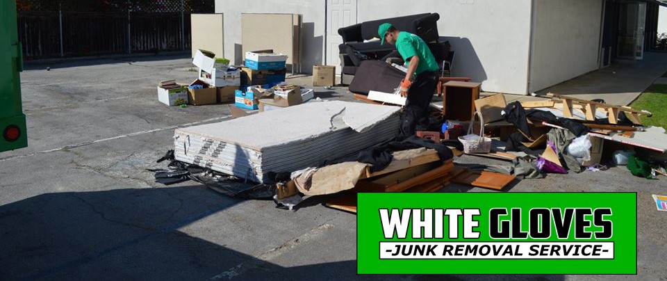 A White Gloves employee hauls unwanted items from outside a property