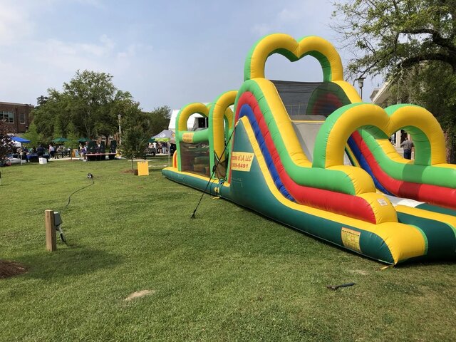 Front view of a green purple and yellow inflatable obstacle course at a real Xtreme setup