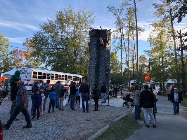 A crowd gathers to watch climbers on Xtreme's mobile rock climbing wall