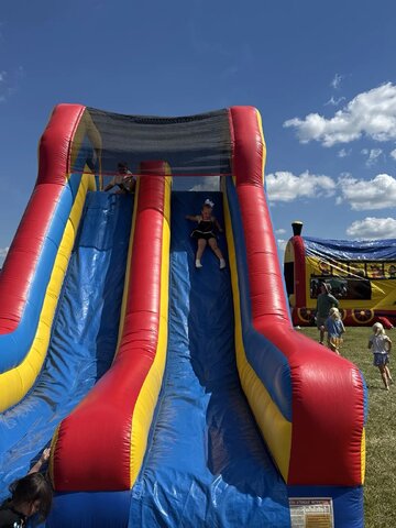 Children enjoying a colorful dual lane inflatable slide at a Xtreme event